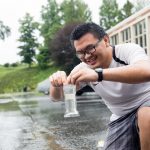 Thinh Bill Pham '20 collects a sample of rainwater from a parking lot on campus