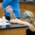 A student carefully measures liquid being poured into a beaker