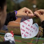 Students wrote heart-shaped messages on a fence in Bell Quad as part of the commemorative service for Matthew Shepard.