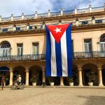 A large Cuban flag drapes over the side of a building