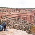 A student sits and looks out into the desert