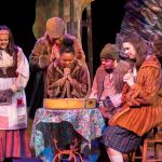 The main characters in the play sit at a table