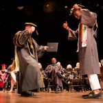 A graduate dances with President Bateman on stage