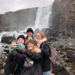 Students take a group selfie in front of a waterfall
