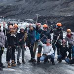 Students raise picks after hiking to the top of a glacier