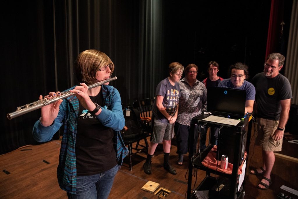 Hailey Gilman plays flute while the rest of the group watches the audio frequency levels