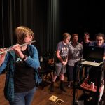 Hailey Gilman plays flute while the rest of the group watches the audio frequency levels