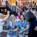 A group of alumnae dance in Michels Plaza