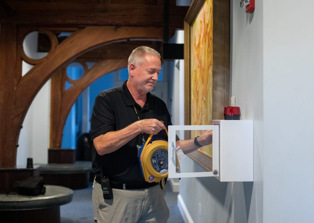 Kris Irwin, director of campus safety, installs an automated external defibrillator (AED) in the Student Center