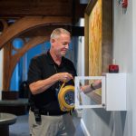 Kris Irwin, director of campus safety, installs an automated external defibrillator (AED) in the Student Center