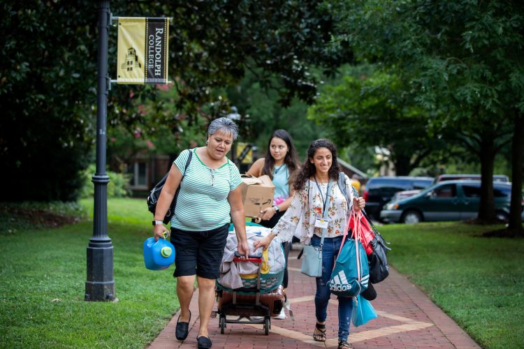 Student and family members wheel luggage along the brick path on front campus Student and family members wheel luggage along the brick path on front campus