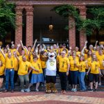 Faculty and staff volunteers pose with Wanda WildCat on the front steps of Main Hall