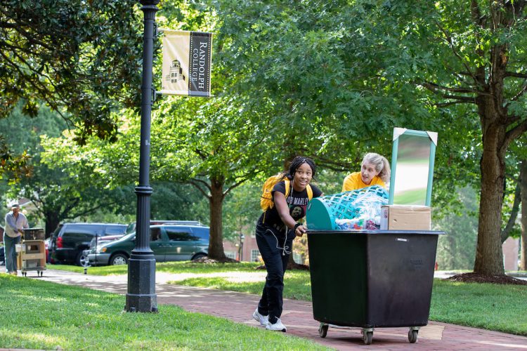 Professor Karin Warren helps a student wheel her room essentials into Main Hall Professor Karin Warren helps a student wheel her room essentials into Main Hall