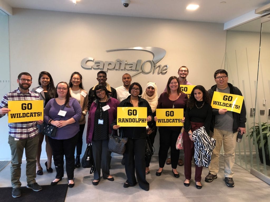 Students and Capital One staff pose with signs that read, 