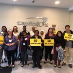 Students and Capital One staff pose with signs that read, 