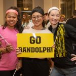 Three students pose with a sign that reads 