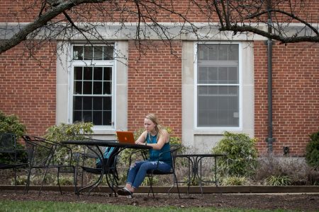 Student studies alone on a patio with a laptop.