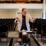 Music professor Randall Speer recorded himself conducting with an accompanist to send to chorale and orchestra students, so they could record themselves performing along to the same master track. The video was shot from multiple angles to give each group a unique view.