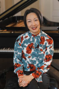 Music professor Emily Yap Chua sis for a portrait in Wimberly Recital hall, sitting in front of a piano 