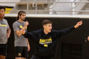 Coach Jordan Leandro gets animated during a practice, spreading both of his arms out as he talks to players. 