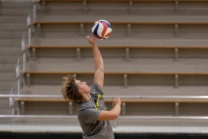 A player on the men's volleyball team jumps up , about the spike the ball over the net.