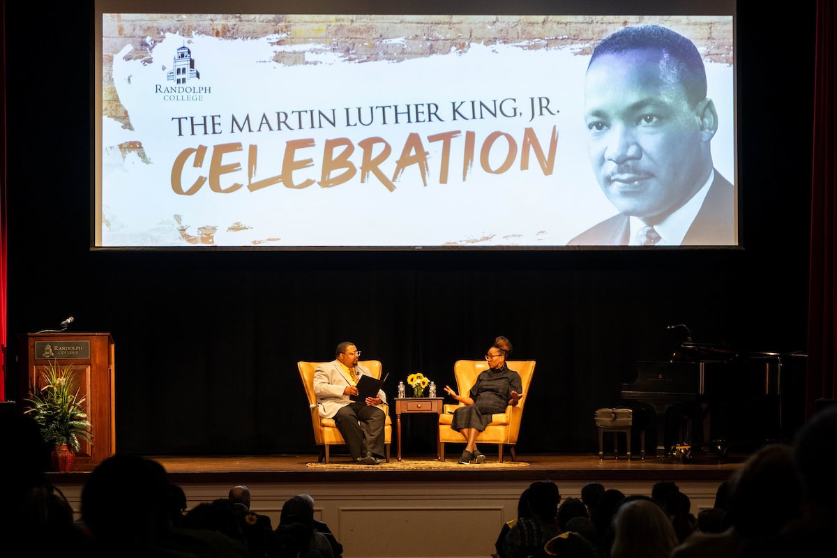 Chief Diversity Officer Charles Gibson III and actress Erika Alexander sit onstage, with a graphic for Randolph's annual MLK Celebration above them.