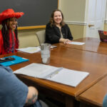 A group of students sits around a conference table, practicing for the Ethics Bowl. They're smiling and laughing with each other. A group of students sits around a conference table, practicing for the Ethics Bowl. They're smiling and laughing with each other.
