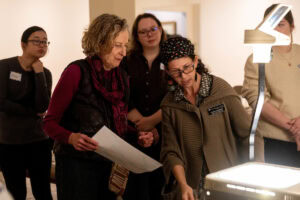 Ann Holsberry and Laura McManus stand in front of a transparency slide, with studnets looking on