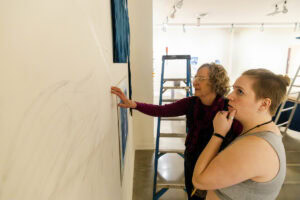 Artist Ann Holsberry works with students to install her work 