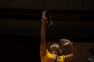 Vajira Mantillake holds a tambourine high into the air dudringa performance