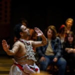 Sudesh Mantillake performs Kandyan dance in Houston Memorial Chapel. The photo is shot from the side, so you see his profile, with one hand raised above his head. Sudesh Mantillake performs Kandyan dance in Houston Memorial Chapel. The photo is shot from the side, so you see his profile, with one hand raised above his head.