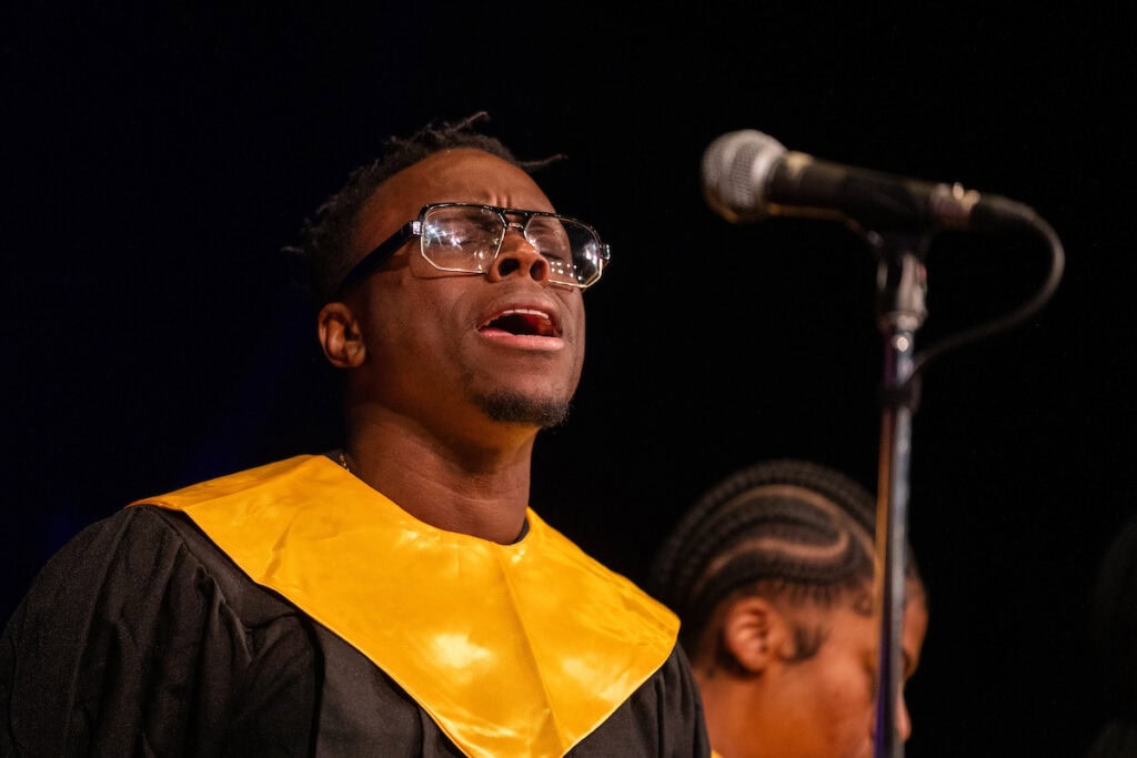 A close-up of a student singing, with a microphone in front of him.