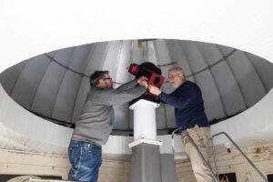 A group of volunteers installs a new telescope inside Winfree Observatory