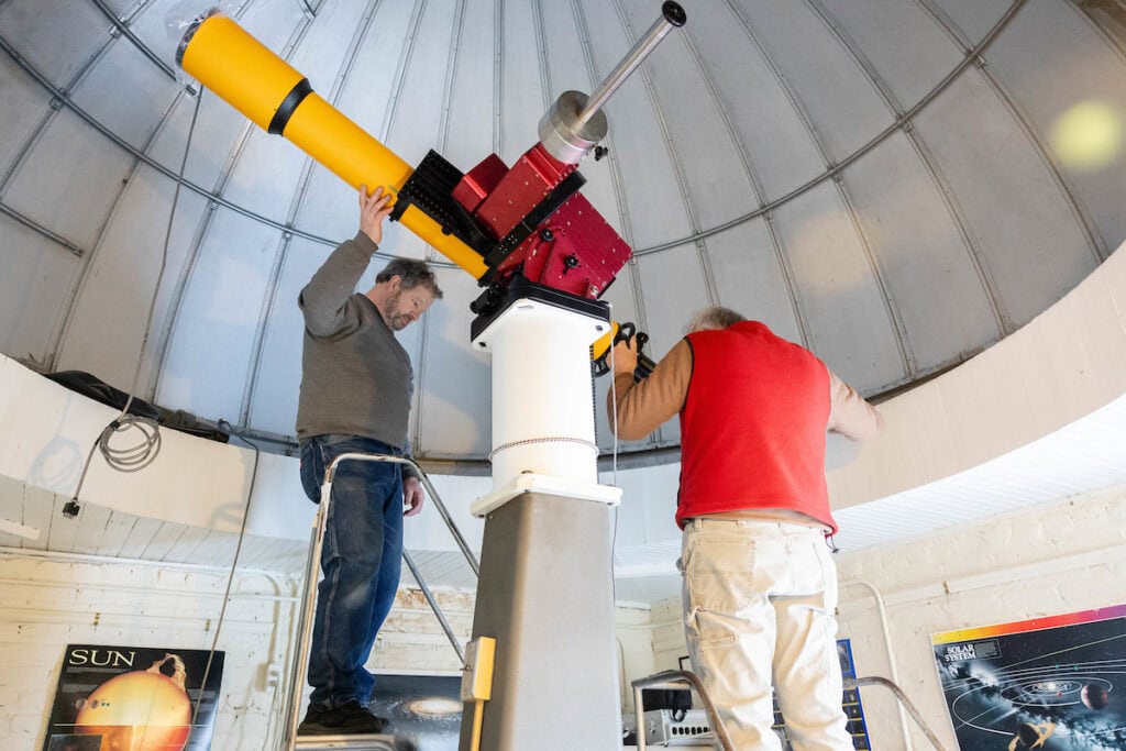 A group of volunteers installs a new telescope inside Winfree Observatory