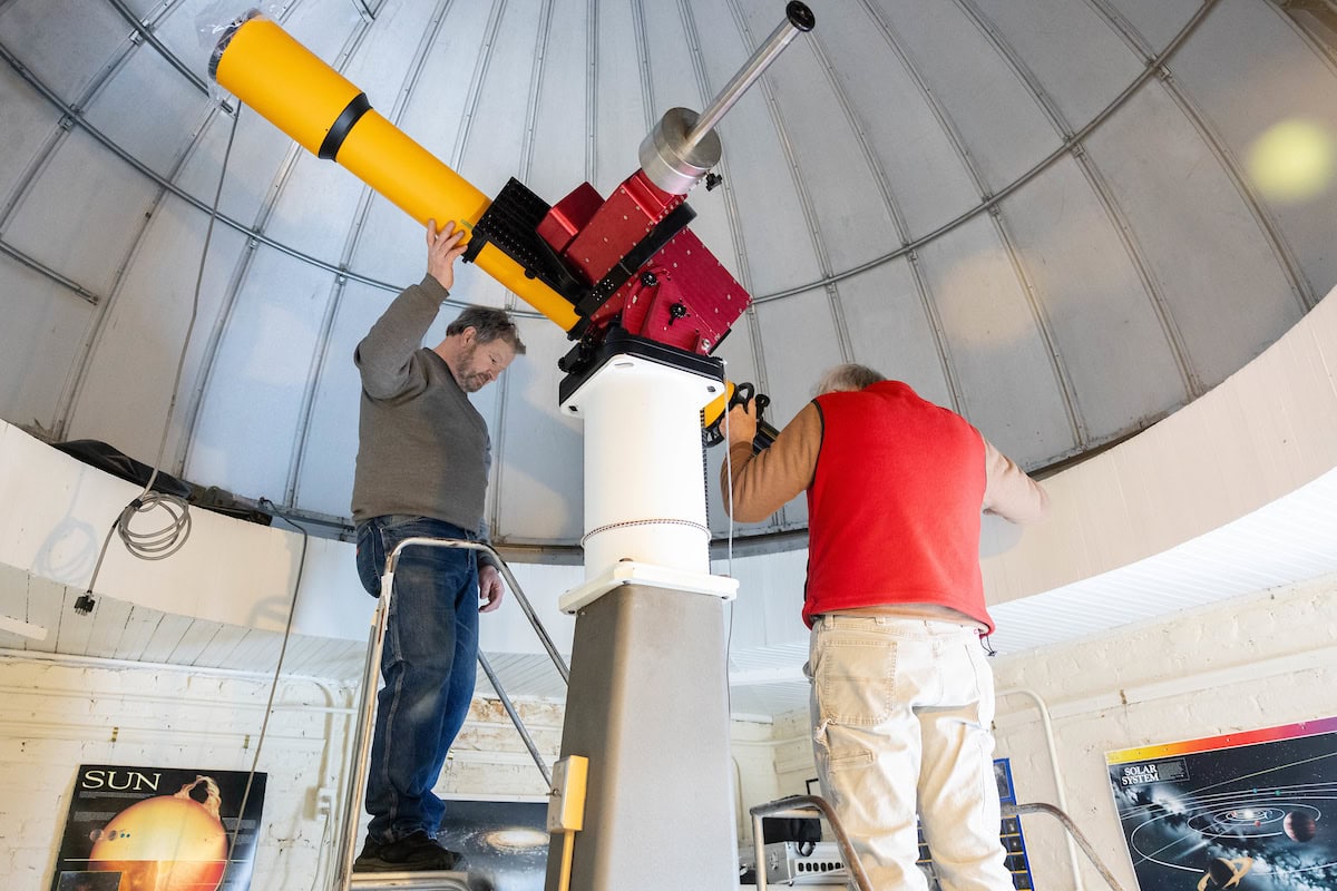 A group of volunteers installs a new telescope inside Winfree Observatory 