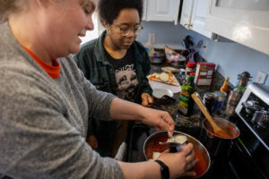 Sarah Sojka and Elizabeth Parsons cook together over a stovetop.