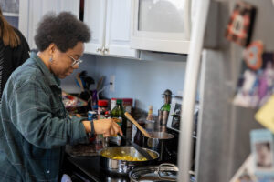 Elizabeth Parsons stirs a sauce on a stovetop as part of an "adulting" class, teaching students life skills.