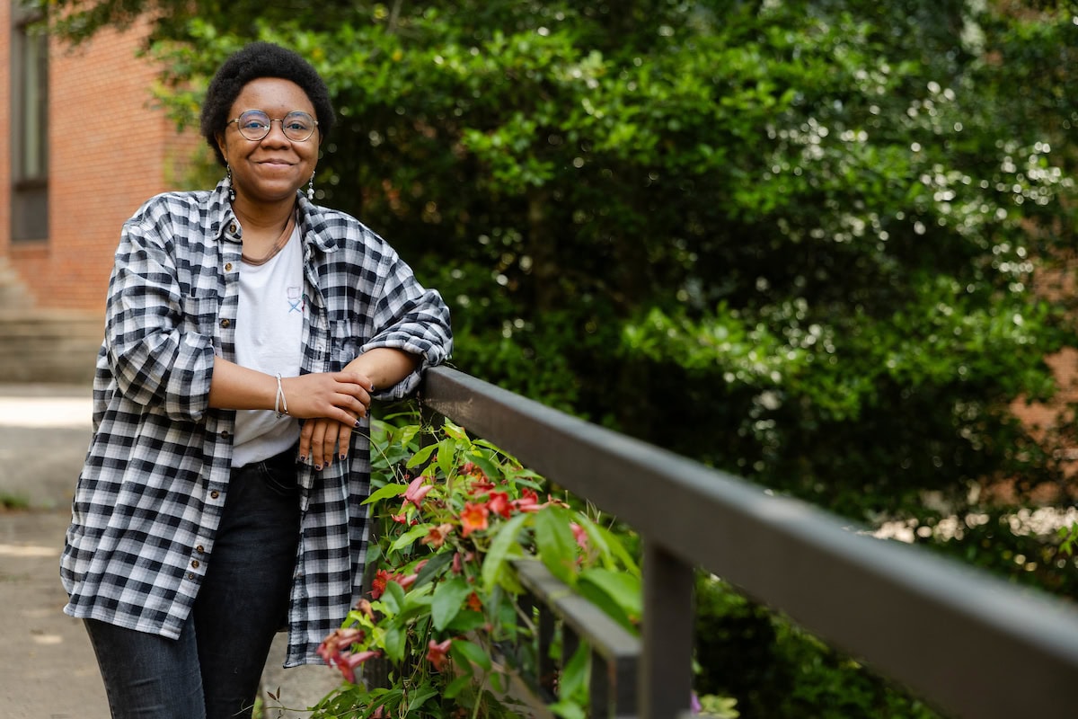 Elizabeth Parsons poses outside on campus, leaning against a railing and smiling at the camera