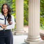 Gianna Cabrera-Castillo poses for a potrait in front of a campus building Gianna Cabrera-Castillo poses for a potrait in front of a campus building