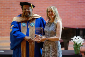 Charles Gibson presents an award to Karin Warren. THey stand together, holding her plaque 