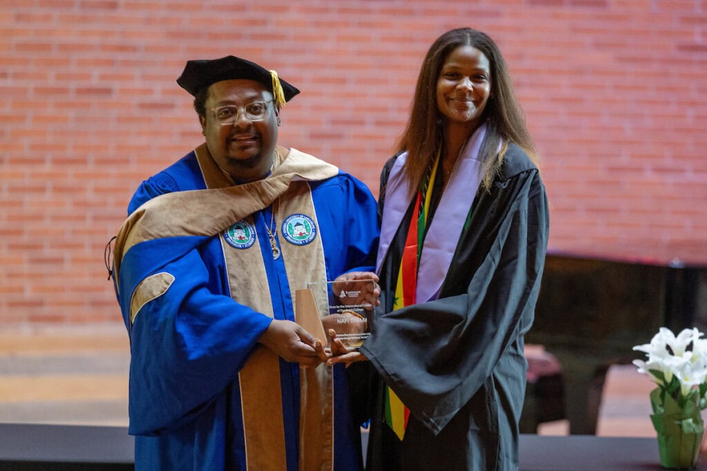 Charles Gibson presents an award to Nafi Thiam '25. They post together, holding her plaque