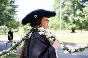A student from the Class of 2025 walks while holding the Daisy Chain