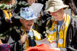 A group of students, several in their robes and button-covered stoles, sing during Daisy Chain