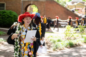 A group of seniors from the Class of 2025 walk and sing while holding the Daisy Chain