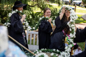 A group of seniors from the Class of 2025 place the Daisy Chain around the Sundial
