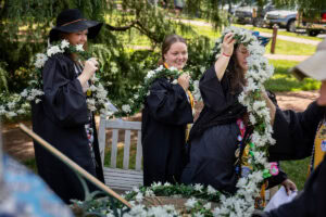 A group of seniors from the Class of 2025 place the Daisy Chain around the Sundial