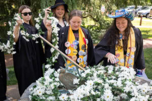 A group of seniors from the Class of 2025 place the Daisy Chain around the Sundial
