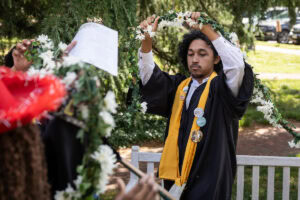 A senior from the Class of 2025 place the Daisy Chain around the Sundial