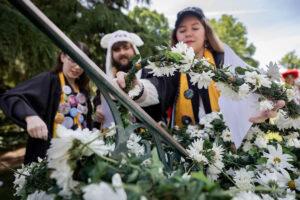A group of seniors from the Class of 2025 place the Daisy Chain around the Sundial