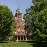 A photo of Main Hall in the spring, with two trees flanking the bell tower
